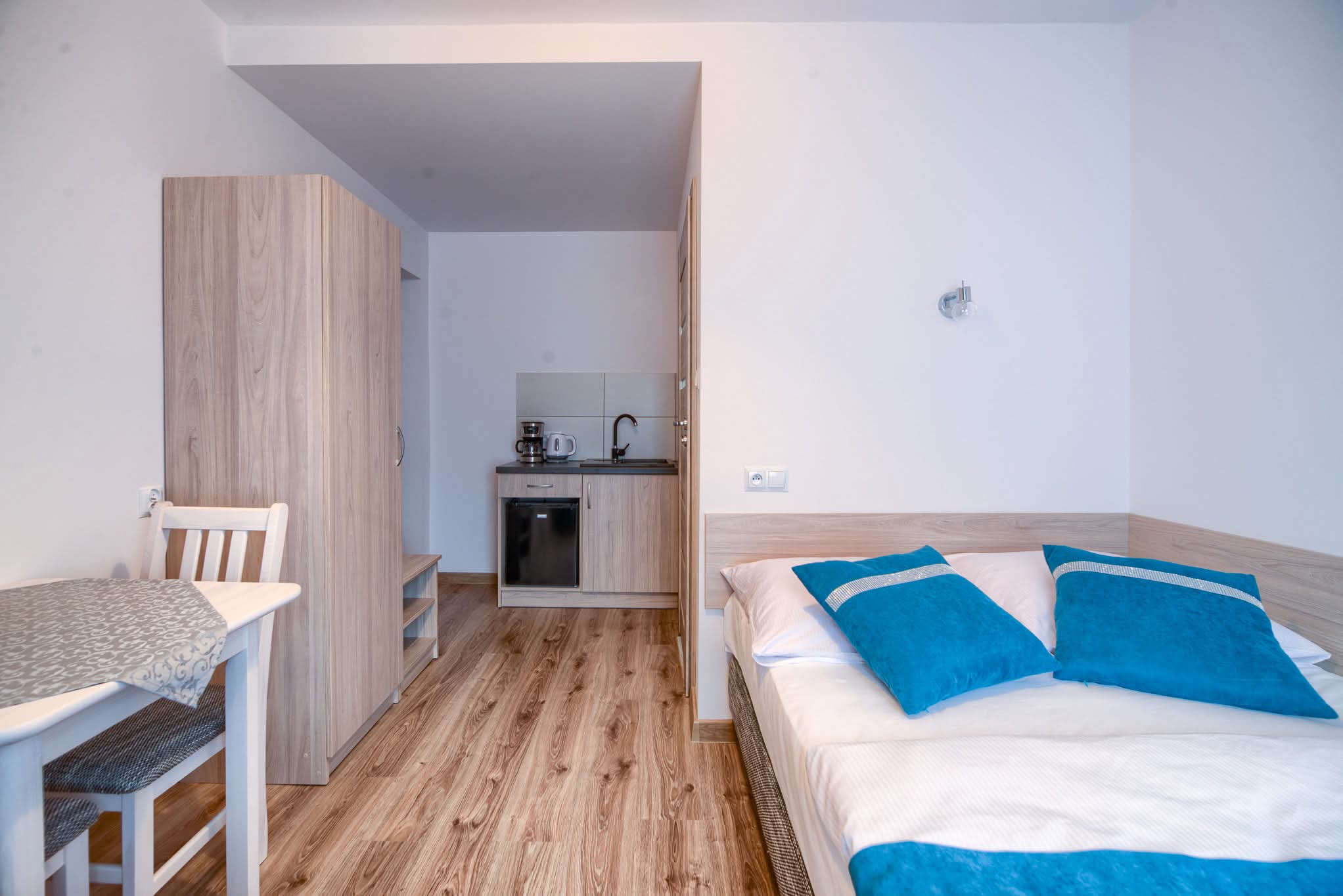 Apartament 2-osobowy- widok na aneks kuchenny, łóżko i szafę